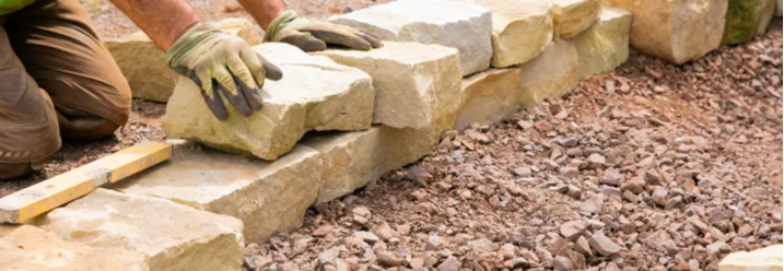 Person baut ein Gartenhaus aus Holz